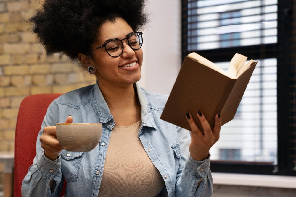 Femme aux cheveux crépus heureuse de lire un livre