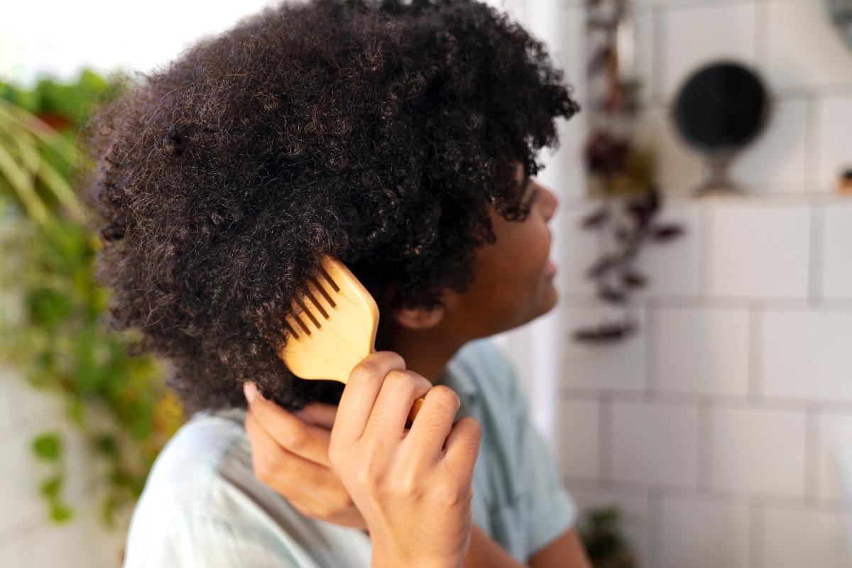 Femme qui peigne ses cheveux avec un peigne afro