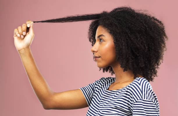 Femme qui étire une mèche de cheveux crépus pour montrer le rétrécissement