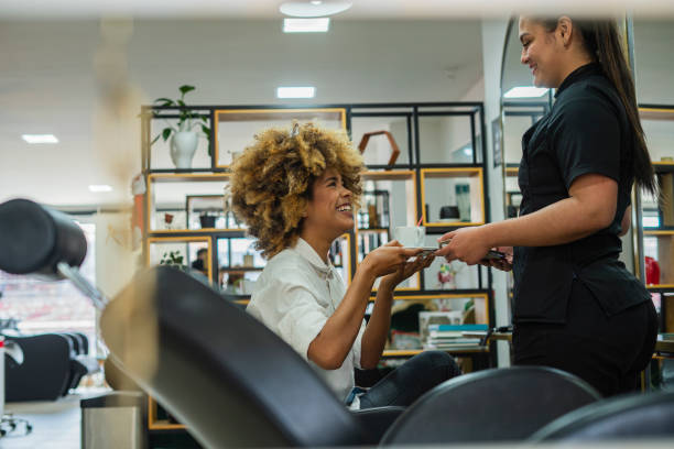 Coiffeuse accueillant une cliente aux cheveux bouclés dans son salon