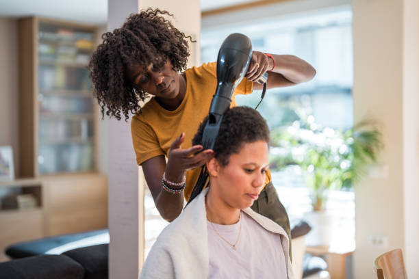 Coiffeur séchant au sèche-cheveux les cheveux d'une cliente en salon