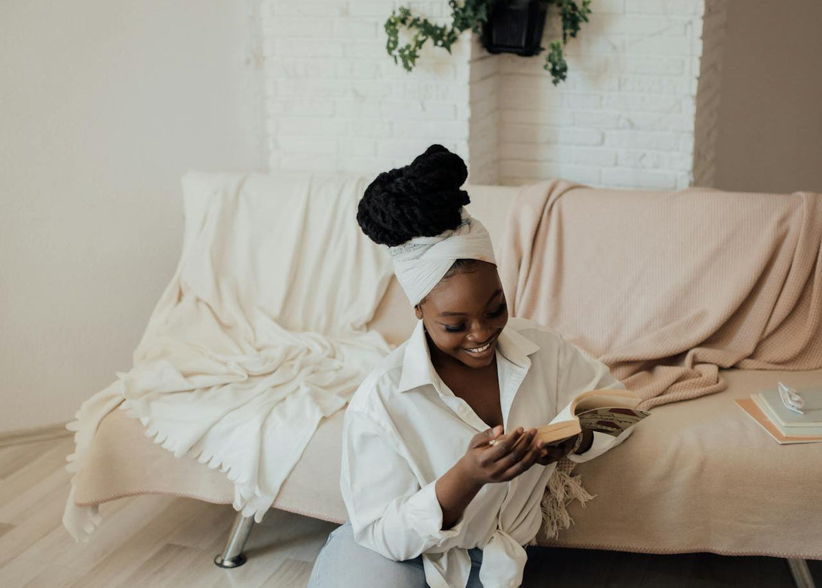 Femme aux cheveux crépus couverts d'un foulard, assise chez elle