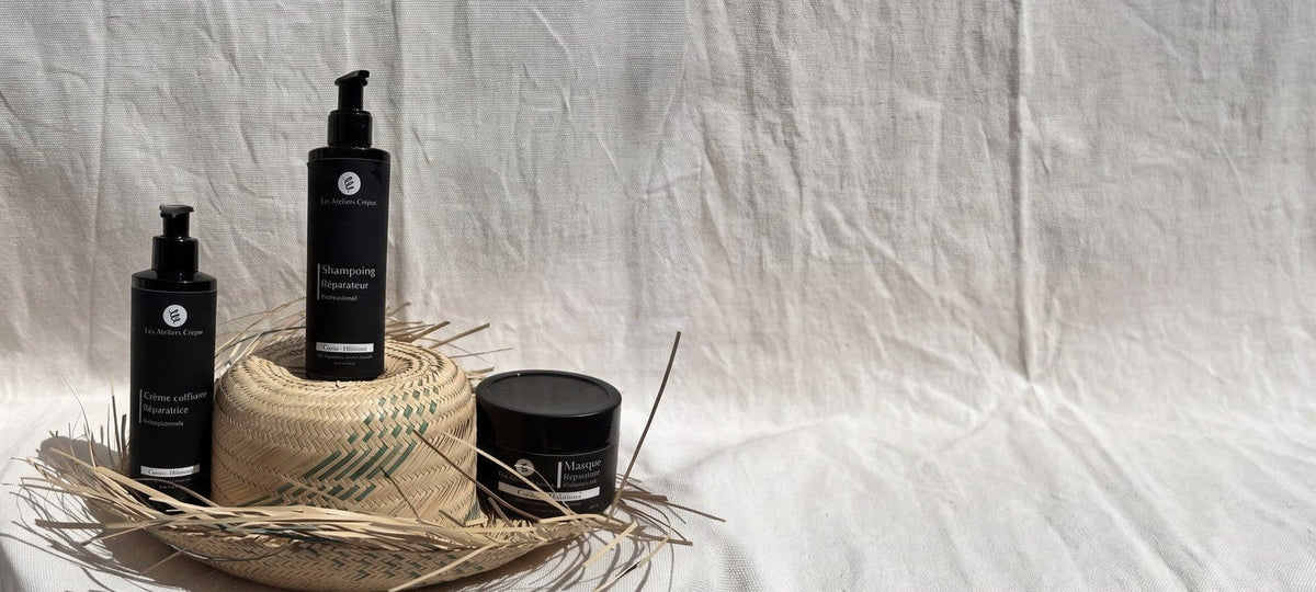 Le Shampoing, La Crème Coiffante et Le Masque Réparateur posés sur un chapeau de paille et un tissu blanc