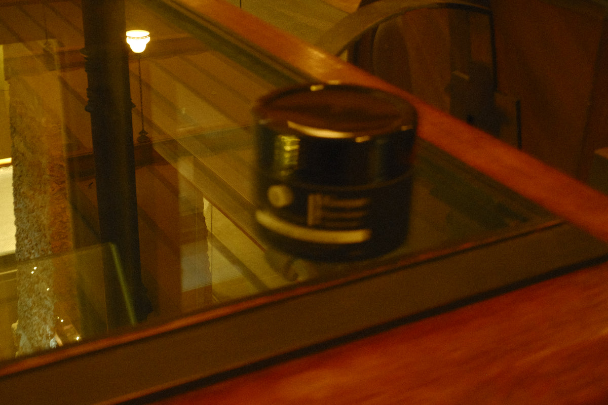 Pot du Masque Réparateur posé sur une table vitrée, sous une lumière chaude