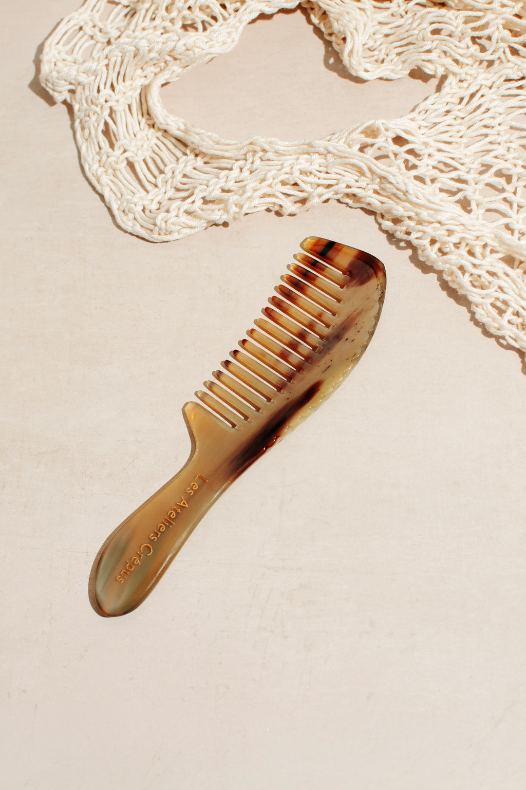 Peigne en corne cheveux crépus Les Ateliers Crepus posé sur fond beige