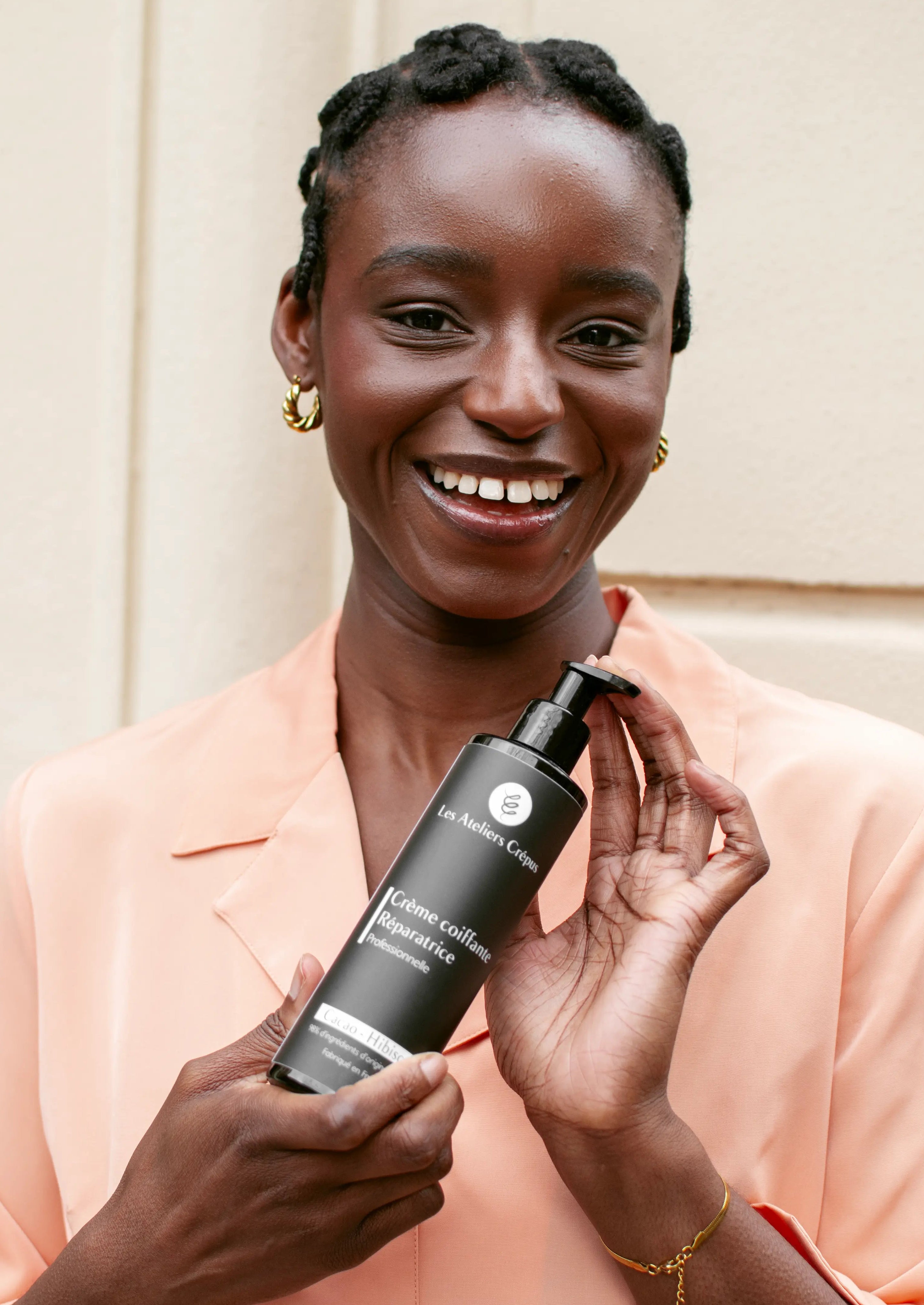 femme noire soin cheveux crépus tressée souriante chemise rose