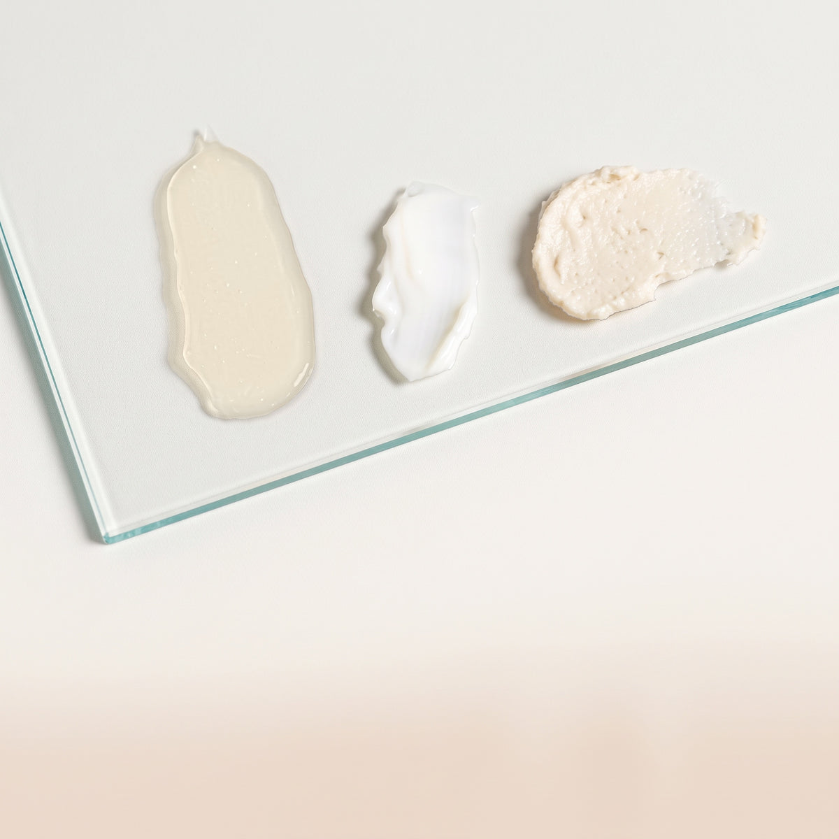 Trois touches de textures crémeuses du Rituel Texture® déposées sur une plaque de verre